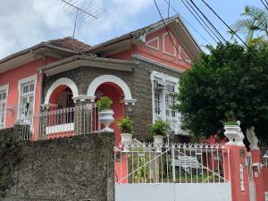 a red house with a white fence in front of it at Casa Aurora Luz do Amanhecer in Rio de Janeiro