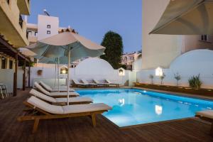 a pool with lounge chairs and an umbrella at Atlantis Hotel in Karpathos