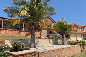 a house with palm trees in front of it at Shellharbour. Ocean, lake and mountain view in Shellharbour