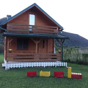 une cabane en rondins avec quatre chaises rouges et jaunes dans l'herbe dans l'établissement Una SI, à Lohovo