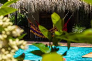 a resort with two hammocks and a thatch roof at Hotel Isabella Tayrona in Los Naranjos