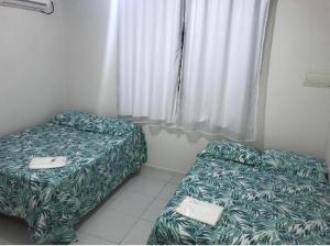 two beds in a small room with a window at Flats Praia do Amor PB in Jacumã