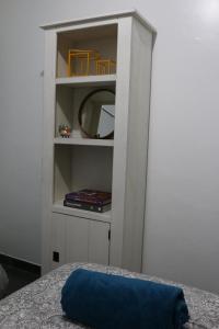 a white book shelf with a mirror and a blue pillow at Casa com Quarto Simples a 4 KM do aeroporto de São José dos Pinhais in São José dos Pinhais