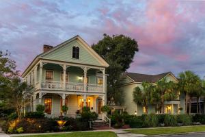 a white house with a porch and palm trees at The Addison on Amelia in Fernandina Beach