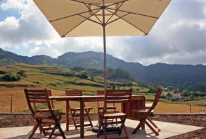 uma mesa de madeira com cadeiras e um guarda-sol em Casa de Almagreira - Empreendimento de Turismo em Espaço Rural - Casa de Campo em Vila do Porto