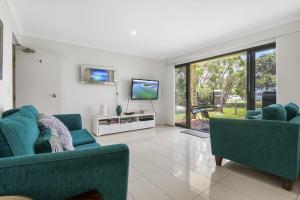 a living room with two blue couches and a tv at Golden Shores Unit 1 21 Landsborough Parade in Caloundra