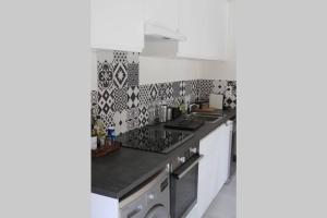 a kitchen with black and white tiles on the wall at Bel appartement 8 personnes à Saint Chaffrey in Saint-Chaffrey