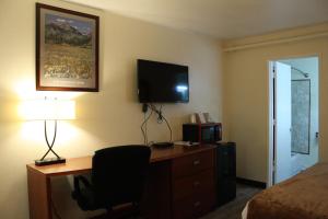 a hotel room with a desk and a bed and a television at Nampa Downtown Inn in Nampa