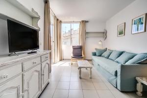 a living room with a blue couch and a flat screen tv at Hauzify I Apartaments Sot del Morer in San Pol de Mar
