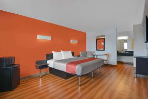 a bedroom with a bed with an orange wall at Motel 6-Cutler Bay, FL in Cutler Bay