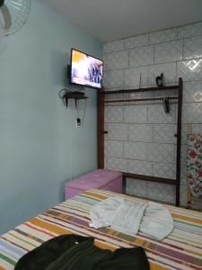 a bedroom with a bed with a tv on the wall at APARTAMENTO SIMPLES E ACONCHEGANTE in Paraty