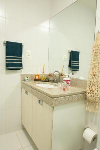 Baño blanco con lavabo y espejo en QUARTO EM CONDOMINIO DE LUXO NA BARRA DA TIJUCA, en Río de Janeiro