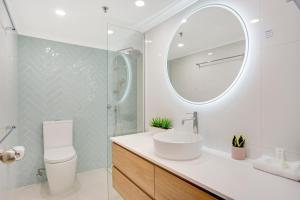 a bathroom with a sink, toilet and mirror at Aegean Resort Apartments in Gold Coast