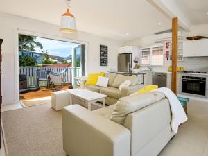 a living room with white furniture and a kitchen at Arklow I Pet Friendly with Ocean Views in Culburra Beach