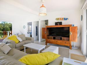 a living room with a couch and a tv at Arklow I Pet Friendly with Ocean Views in Culburra Beach