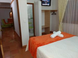 a hotel room with a bed with a television and a room with at Apartahotel La Gran Familia in Villa de Leyva