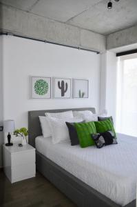 a bedroom with a large bed with green and white pillows at Cozy Stays Cayala Apartments 2 in Guatemala