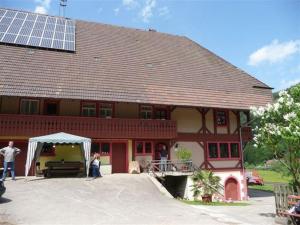 un gran edificio rojo con techo solar con gente parada fuera en Wäldebauernhof, en Gutach