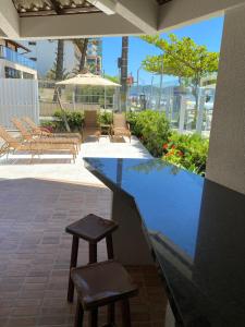 un patio con 2 taburetes y una piscina en Apartamento Aconchegante Beira Mar em Itapema - Santa Catarina, en Itapema