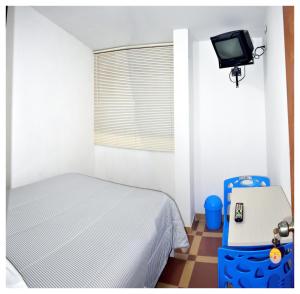 - une chambre avec un lit et une télévision murale dans l'établissement Hospedaje La Casa Blanca, à Urbanizacion Buenos Aires