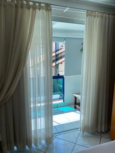 Habitación con cortinas blancas y ventana grande. en Apartamento Aconchegante Beira Mar em Itapema - Santa Catarina, en Itapema