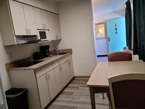 a kitchen with white cabinets and a table and a microwave at Motel 9 Las Cruces in Las Cruces