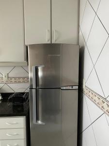 Un refrigerador de acero inoxidable en una cocina con gabinetes blancos. en Apartamento Aconchegante Beira Mar em Itapema - Santa Catarina, en Itapema