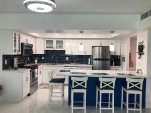 a kitchen with white cabinets and a blue island with bar stools at The Blue Island in Miami Beach