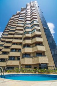 a tall building with a pool in front of it at Flat Golden Fortaleza in Fortaleza