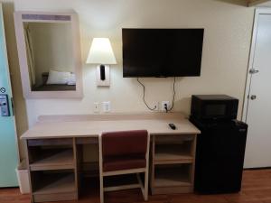 a desk in a hotel room with a television and a bed at Motel 9 Las Cruces in Las Cruces