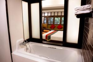 a bathroom with a tub and a mirror at Yantarasri Resort in Chiang Mai