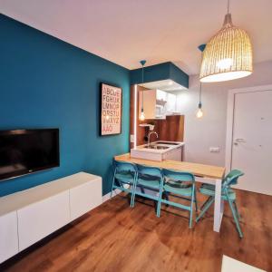 a kitchen with blue walls and a wooden table and chairs at Apartamento RAL5021 en Triana junto al centro in Seville