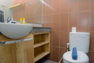 a bathroom with a white toilet and a sink at Comfortable and Beautiful 1BR Apartment at Atlanta Residence By Travelio in Pondokcina +5 photos