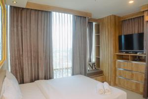 a bedroom with a bed and a tv and a window at Comfortable and Beautiful 1BR Apartment at Atlanta Residence By Travelio in Pondokcina