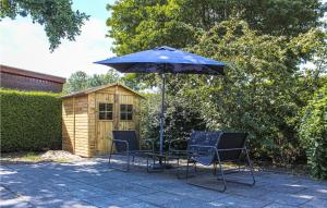 a table and chairs under an umbrella next to a shed at Nice stacaravan In Tzummarum With Outdoor Swimming Pool in Tzummarum