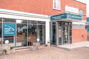 una tienda frente a un edificio de ladrillo con ventanas en Airport Lounge Hotel Düsseldorf, en Düsseldorf