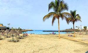 a beach with chairs and palm trees and the ocean at Barco Pita - Amarilla Marina in San Miguel de Abona