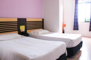 2 camas en una habitación de hotel con sábanas blancas en Hotel Lam Seng en Pantai Remis