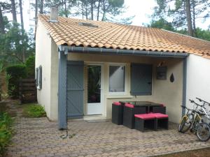 une petite maison avec des tabourets rouges devant elle dans l'établissement Tres agreable maison au calme dans la pinede, à Lacanau-Océan