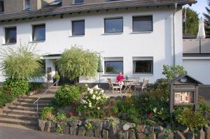 a woman sitting at a table in front of a house at Haus Barbara in Hilders