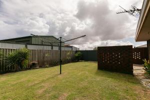 um quintal com uma cerca e um cesto de basquetebol em Apparition Apartments em Geraldton