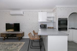 a white kitchen with a counter and a table at Apparition Apartments in Geraldton