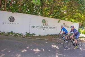 two men riding bikes down a street next to a wall at The Cellars-Hohenort in Cape Town