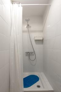a white bathroom with a shower with a blue rug at Bee Hostel in Limassol