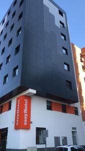 ein hohes Gebäude mit einem orangenen Schild darauf in der Unterkunft easyHotel Malaga City Centre in Málaga