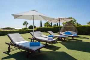 a row of lounge chairs and umbrellas on a lawn at Villa Savoya Sunrise by Ezoria Villas in Coral Bay