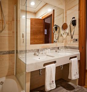 a bathroom with a sink and a mirror and a tub at Hotel Campos de Baeza in Baeza
