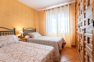 1 dormitorio con 2 camas y ventana en Apartamentos Sierra Tejeda, en Alcaucín