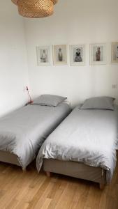 two beds in a white room with pictures on the wall at Belle Malouine in Saint Malo