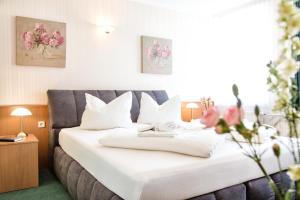 a hotel room with a bed with white sheets and flowers at Hotel Stadt Berlin in Jessen